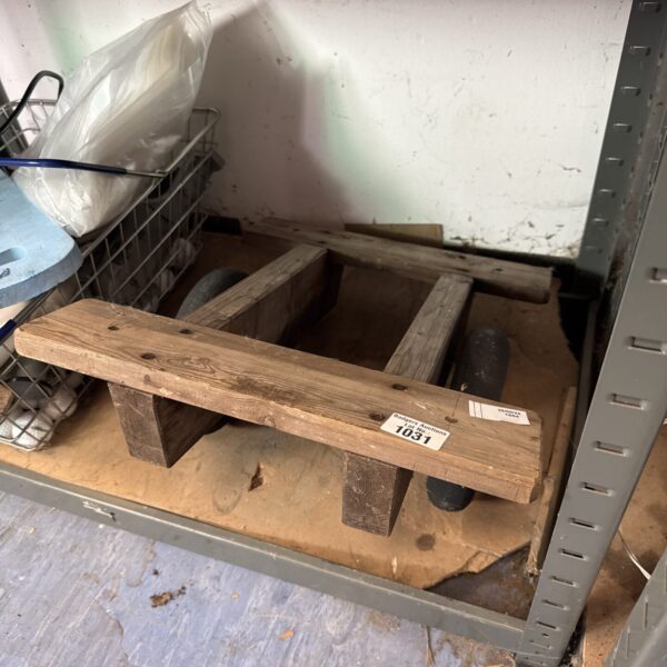 Vintage wooden dolly with two wheels for moving heavy items.