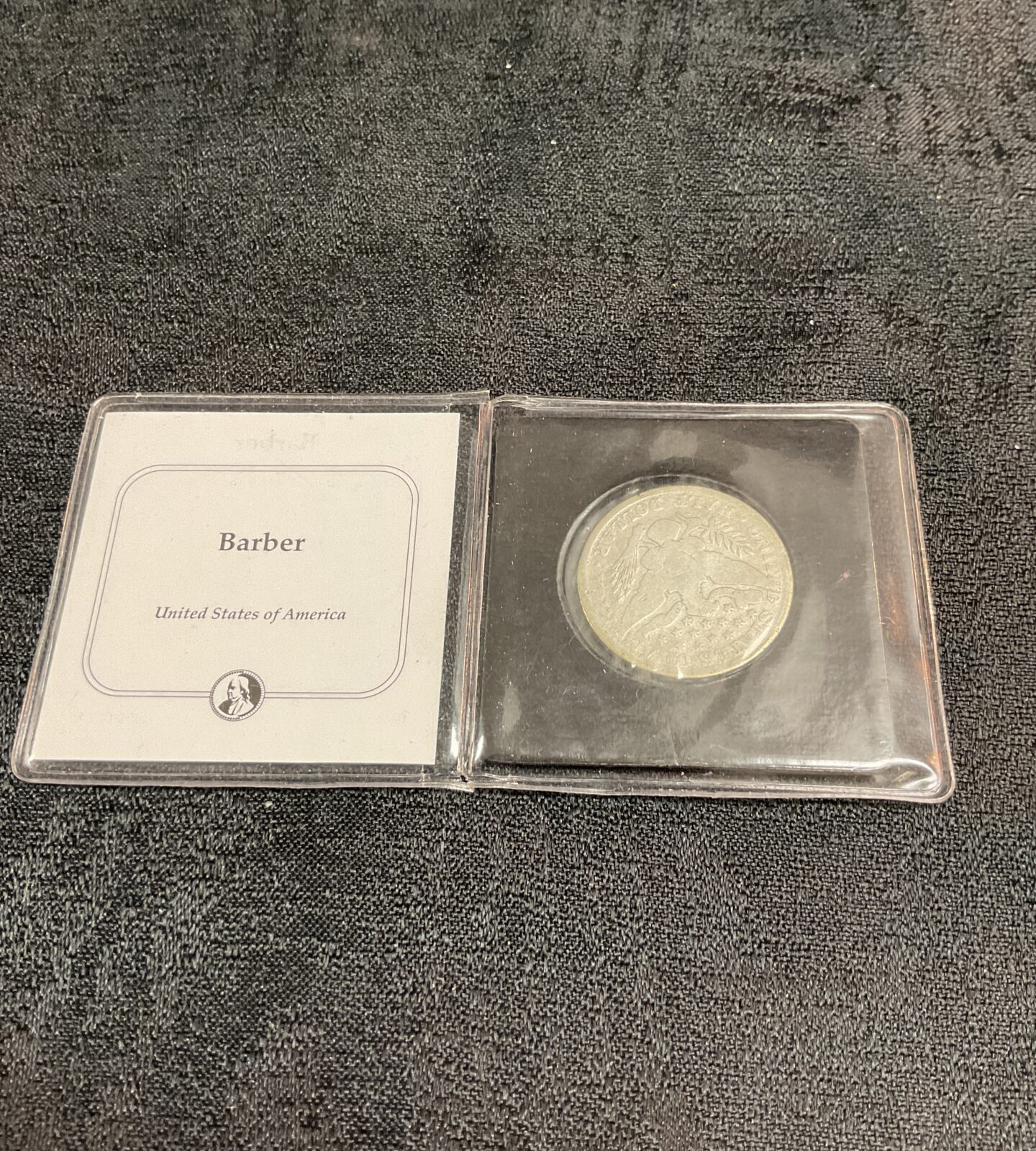 Reverse of an 1891 Barber Silver Half Dollar coin in protective case.