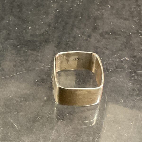 Close-up of a 925 silver square ring, minimalist design.