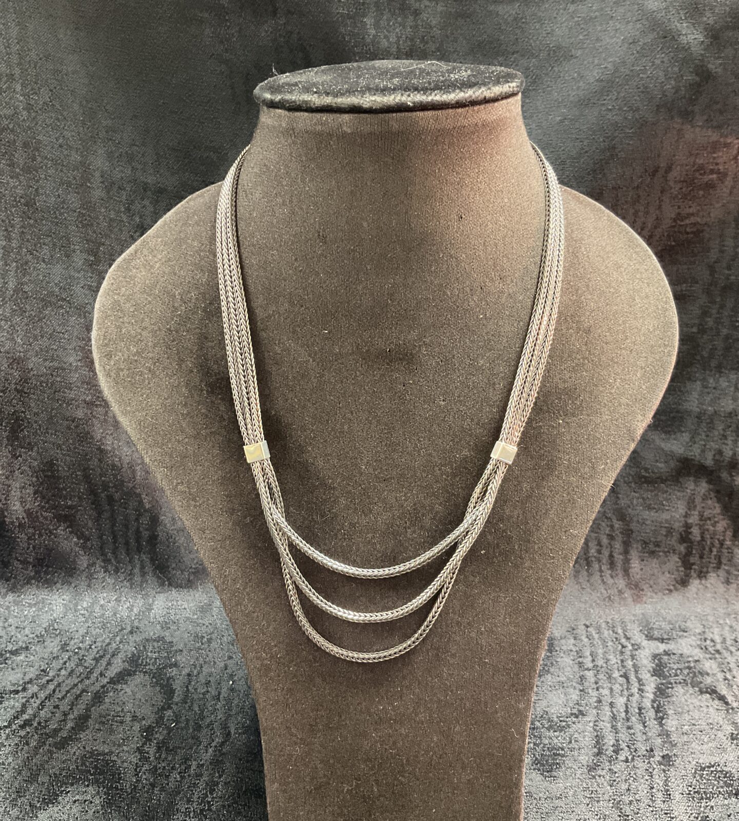 Elegant 925 silver three-strand necklace on display.