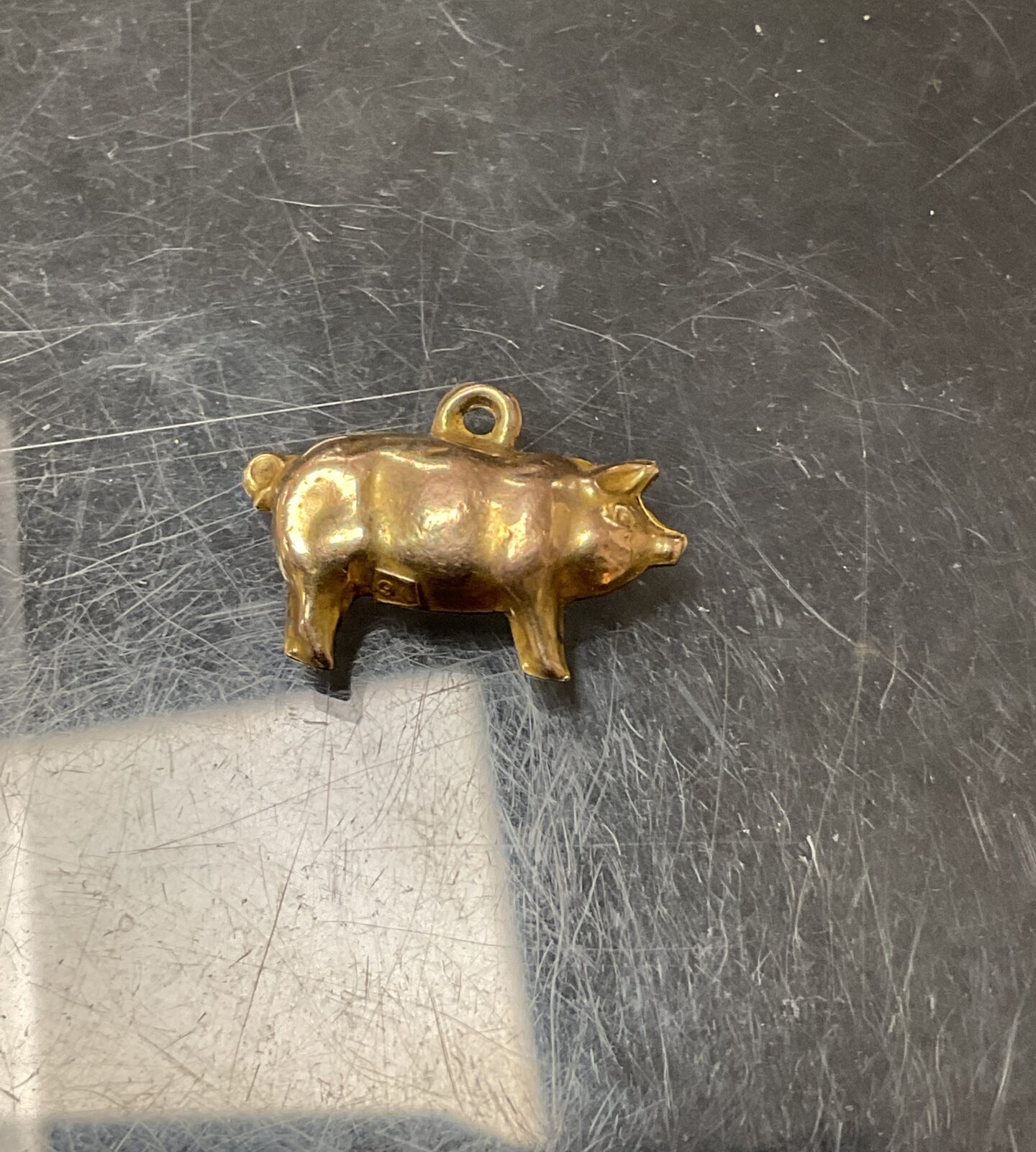 Close-up of a 9ct gold pig charm with detailed features.