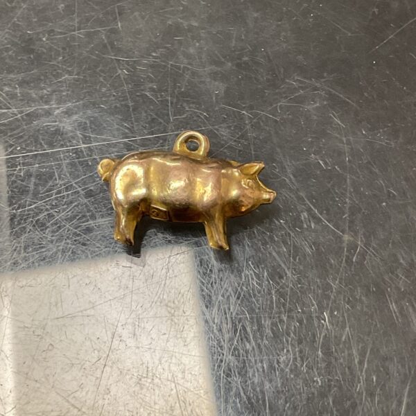 Close-up of a 9ct gold pig charm with detailed features.