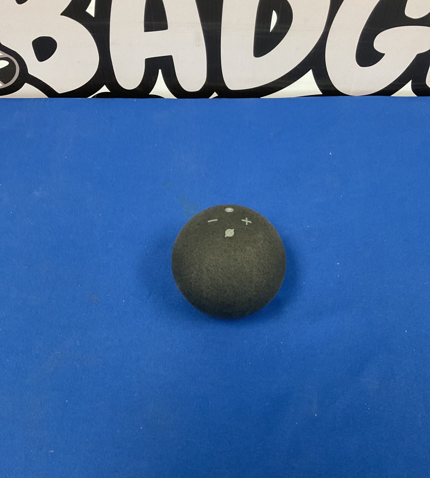 Black Amazon Alexa Echo Dot B7W64E smart speaker on a dark surface.