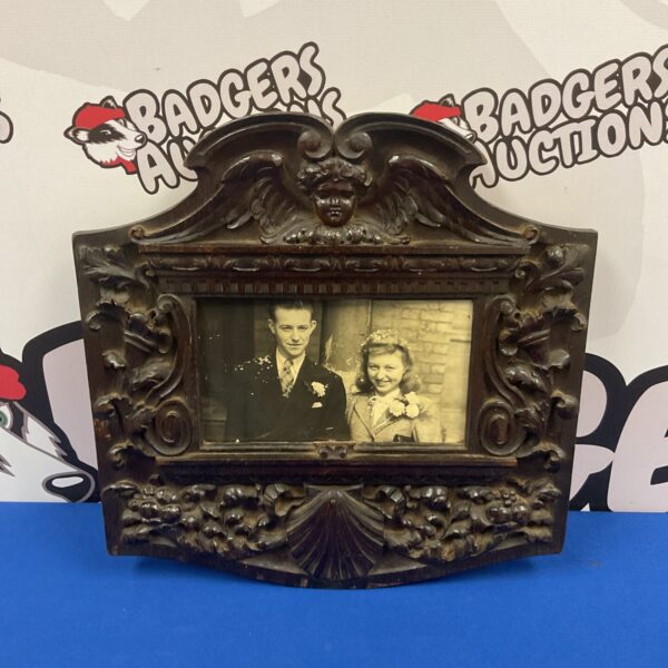 Intricately carved antique Black Forest photo frame with a vintage photograph.