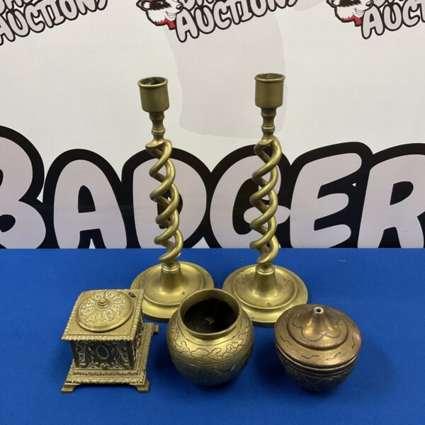 Antique brass candlesticks, tobacco jar, and pot on a blue surface.