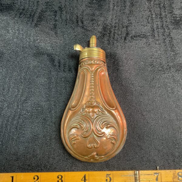 Intricate antique copper powder flask with embossed floral design.