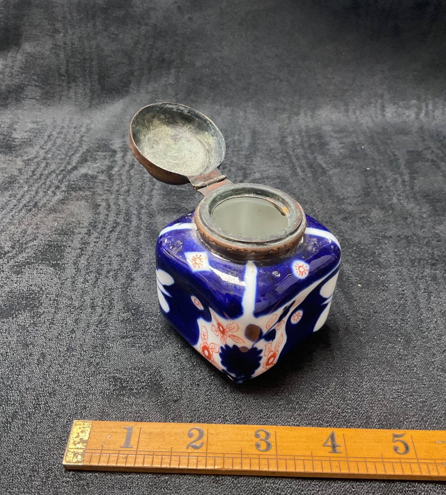 Side view of antique Imari inkwell with ruler for scale.