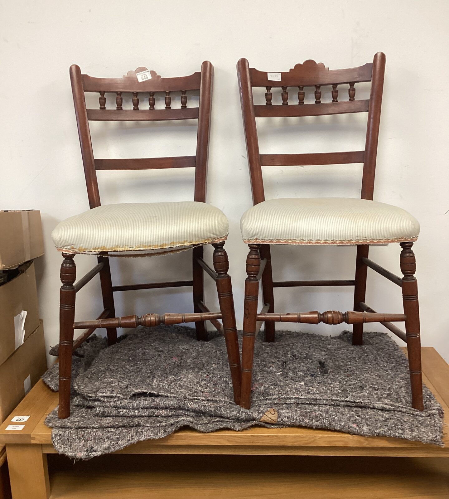 Pair of antique mahogany bedroom chairs with worn upholstery.