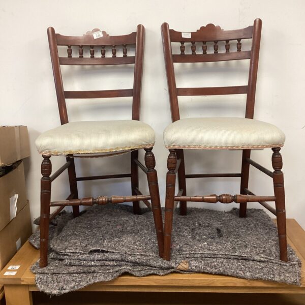 Pair of antique mahogany bedroom chairs with worn upholstery.