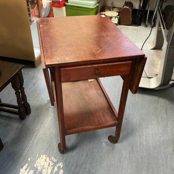 Side view of antique mahogany tea trolley with extending leaves.