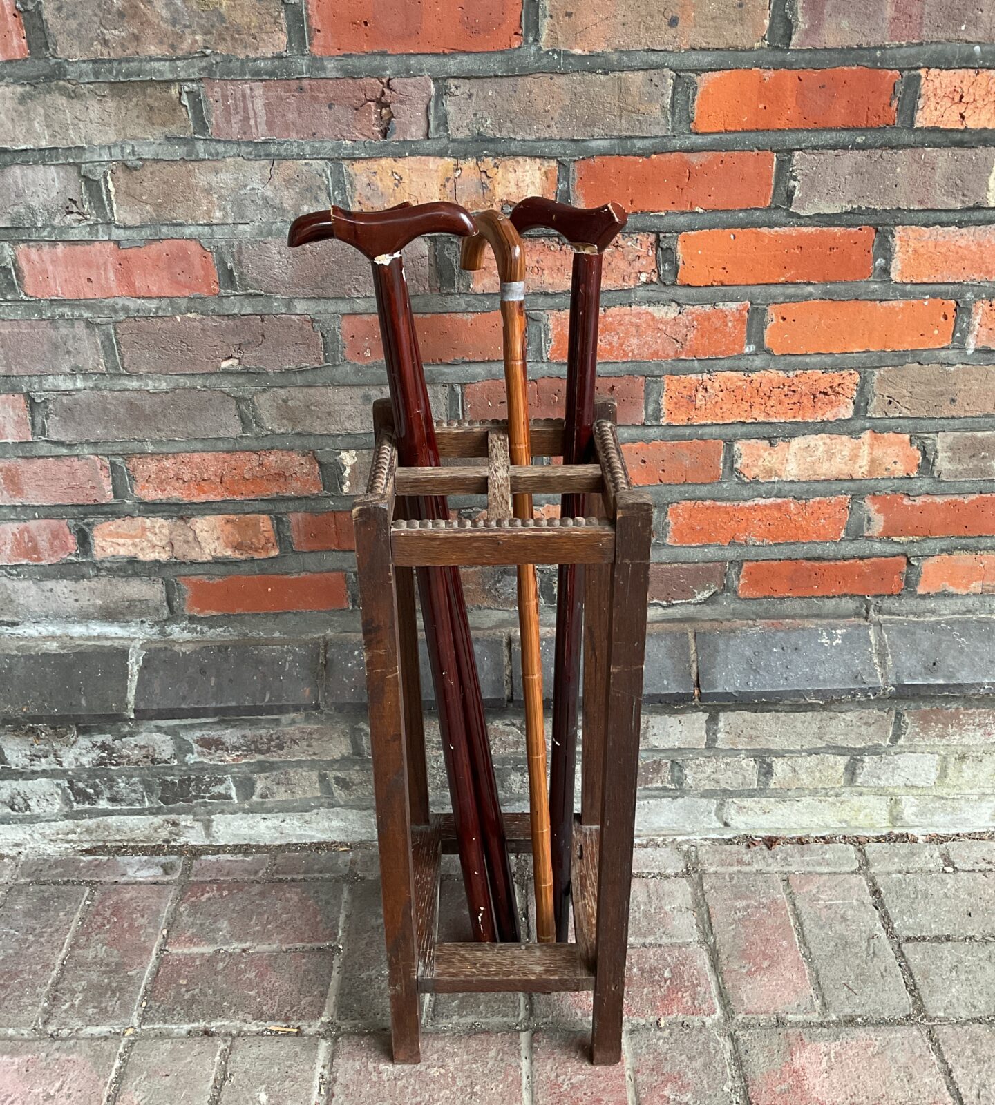 Antique oak walking stick stand with walking sticks displayed.
