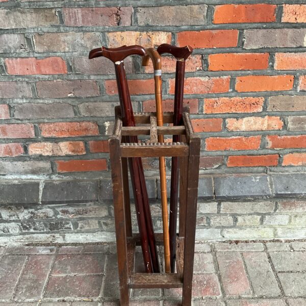 Antique oak walking stick stand with walking sticks displayed.