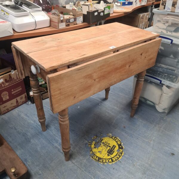 Antique pine drop leaf table with hinged leaves and turned legs.