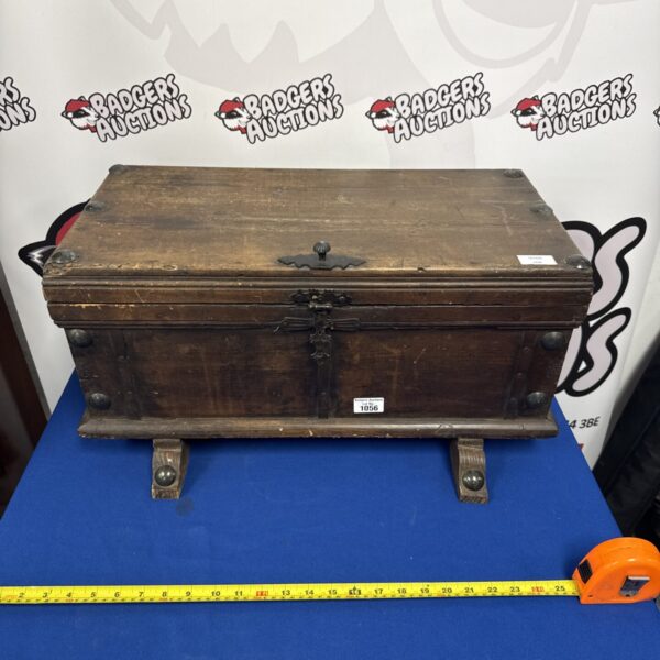 Front view of antique wooden storage box with metal clasp.