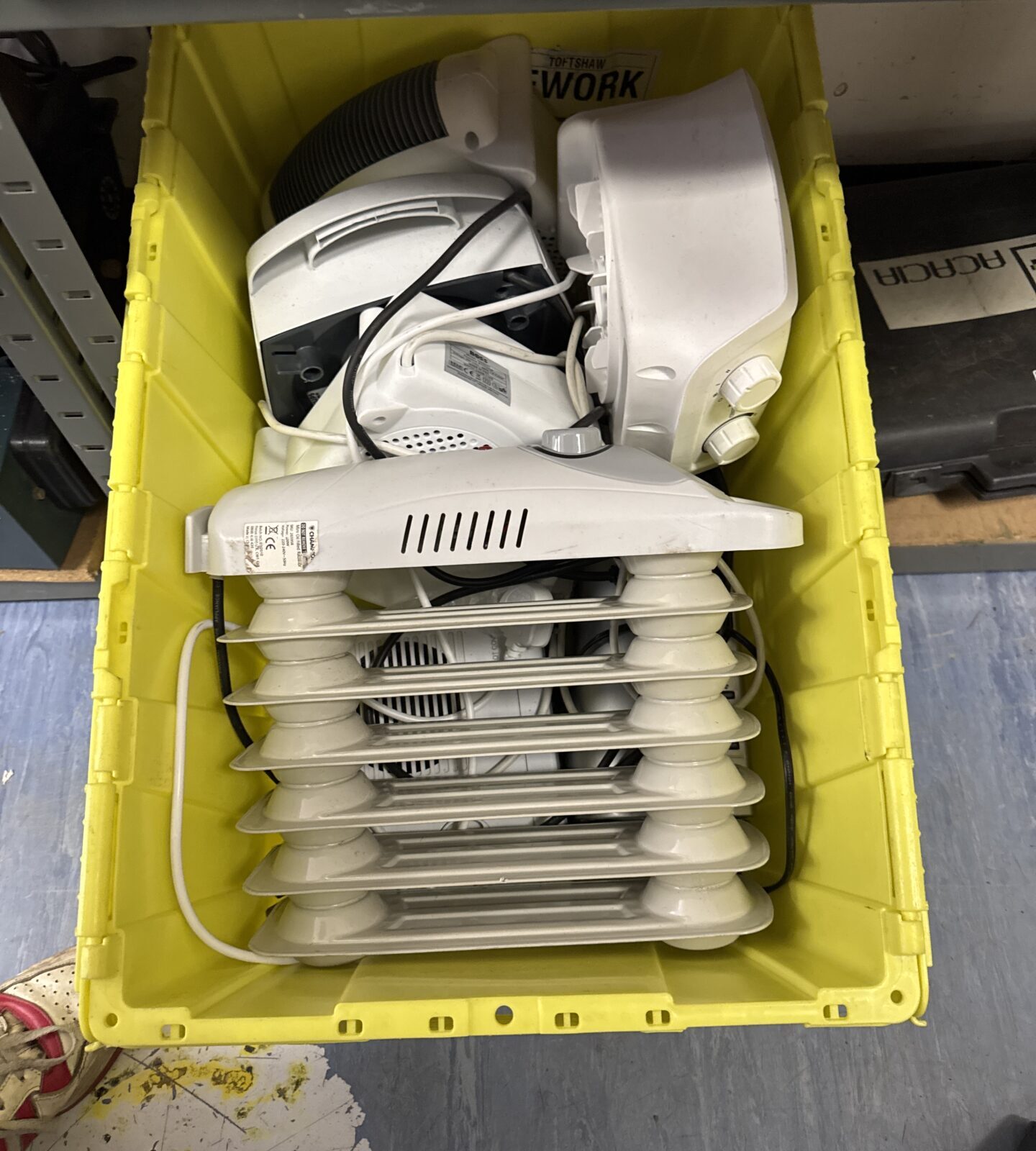 Assorted electric heaters in a tote crate, portable heating appliances.