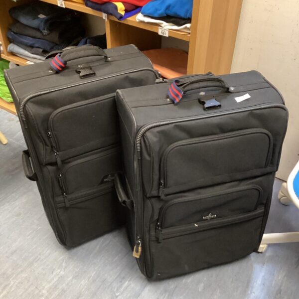 Pair of black Atlantic rolling suitcases with extendable handles.
