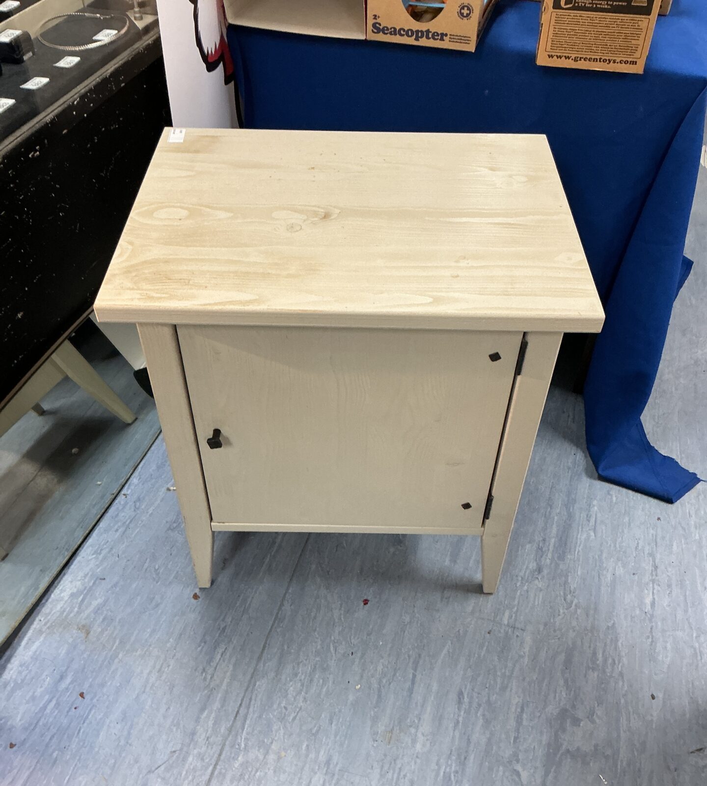 Light wood bedside cabinet with a single door.