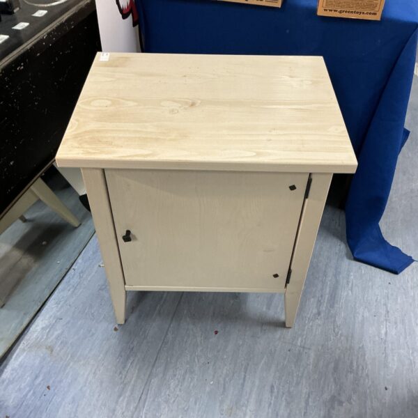 Light wood bedside cabinet with a single door.