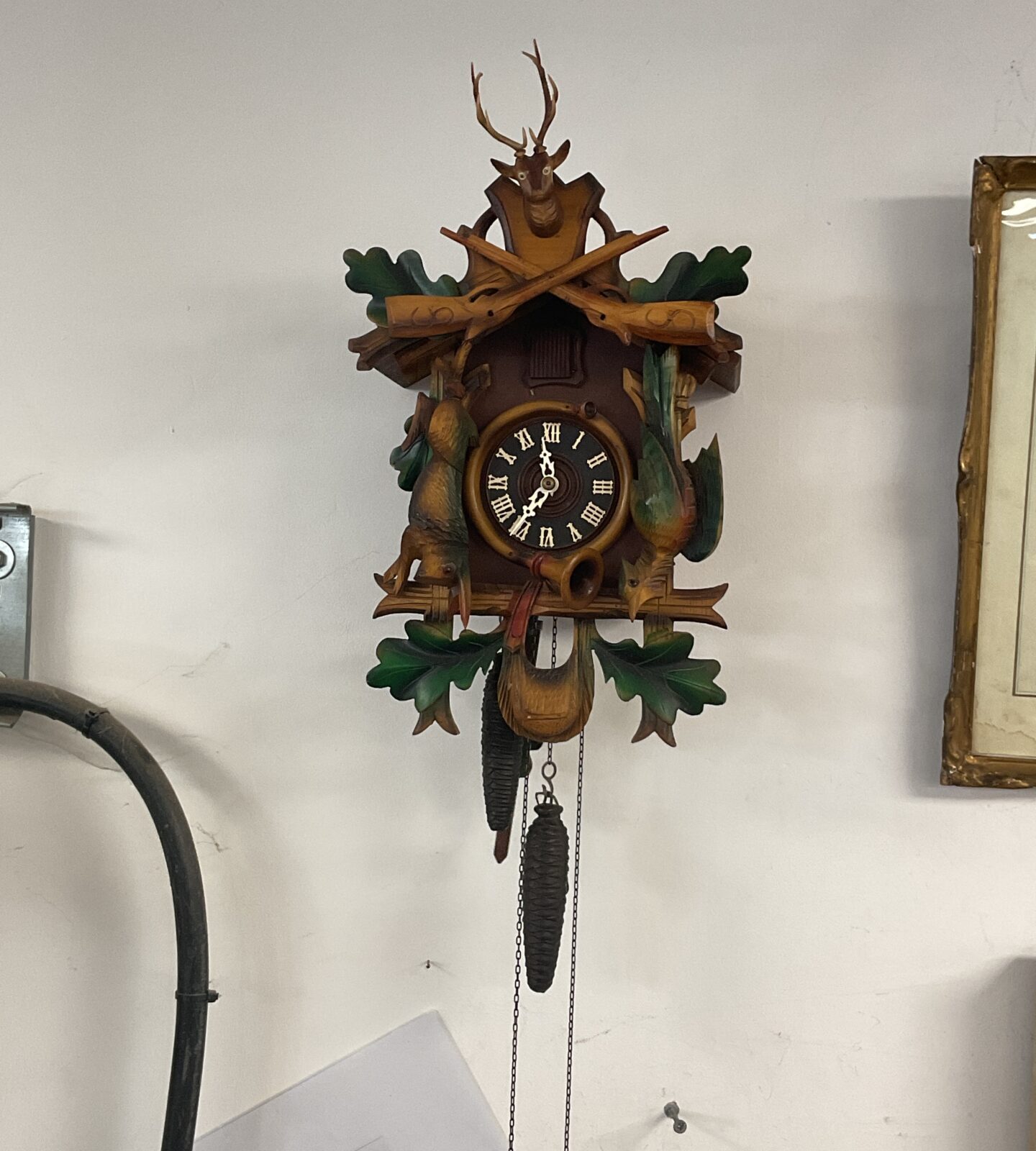 Vintage Black Forest cuckoo clock with detailed hunting scene carvings.