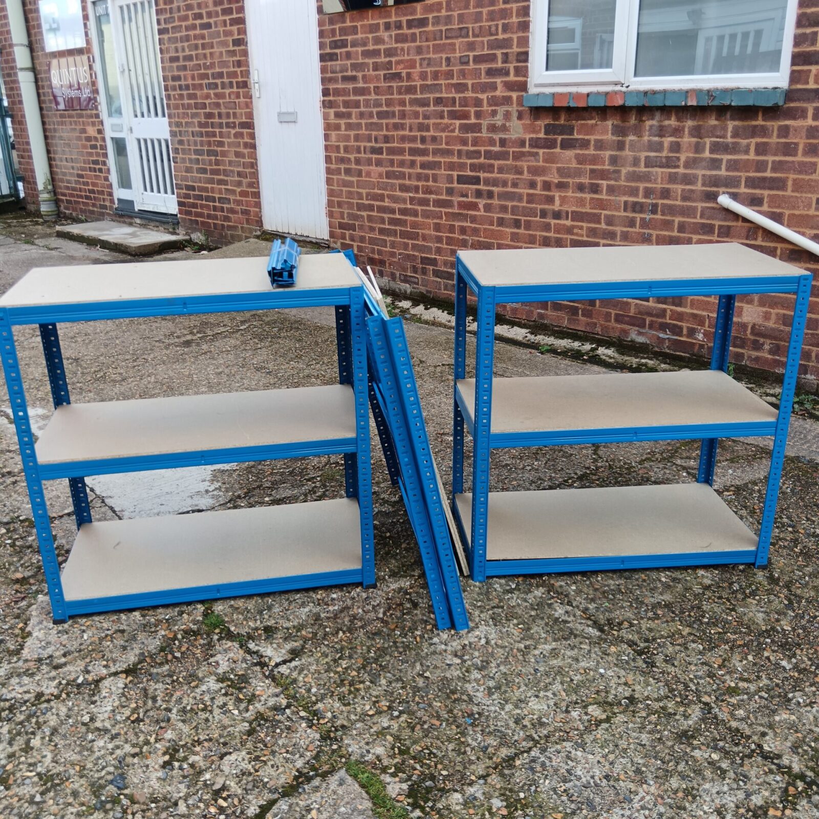 Three blue metal shelving racks for storage.