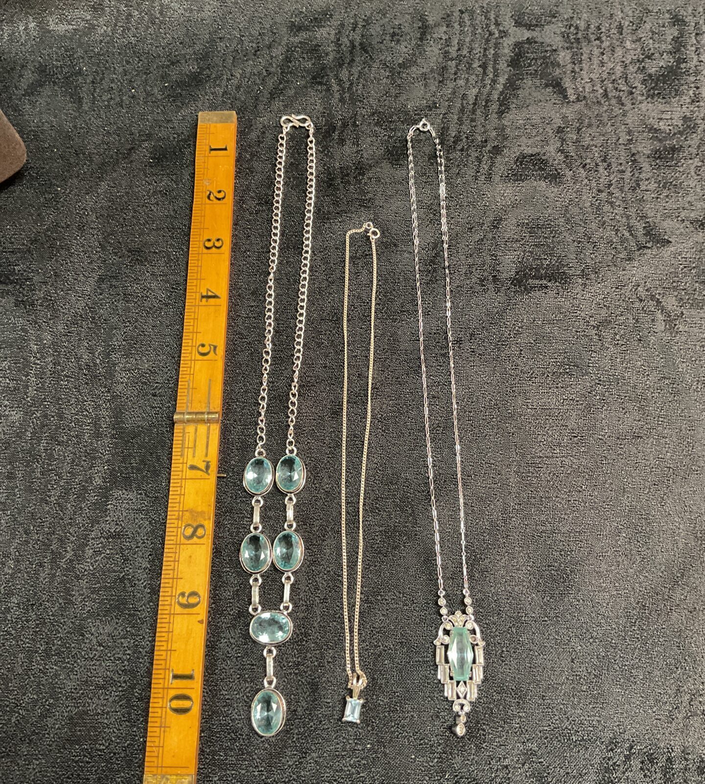 Collection of three silver necklaces with blue topaz pendants.