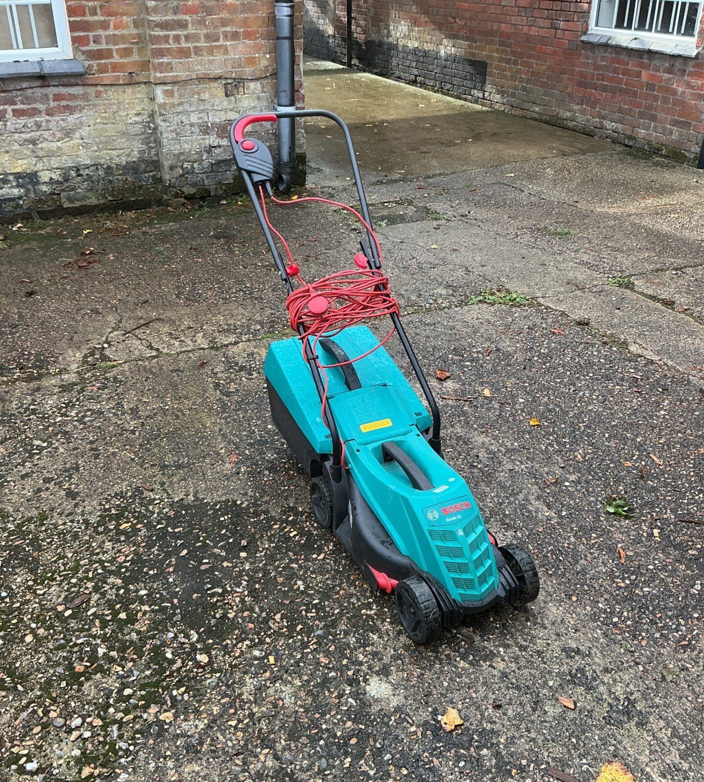 Used Bosch electric lawnmower in a garden setting.