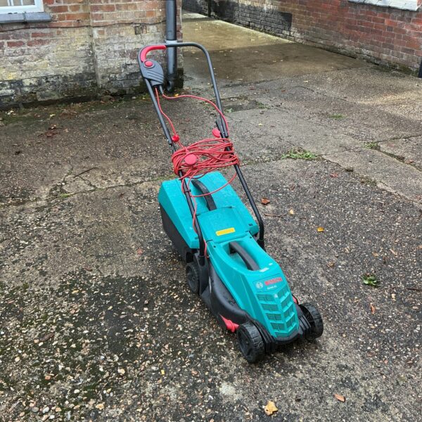 Used Bosch electric lawnmower in a garden setting.