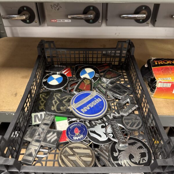 Tray of assorted vintage car badges and emblems.