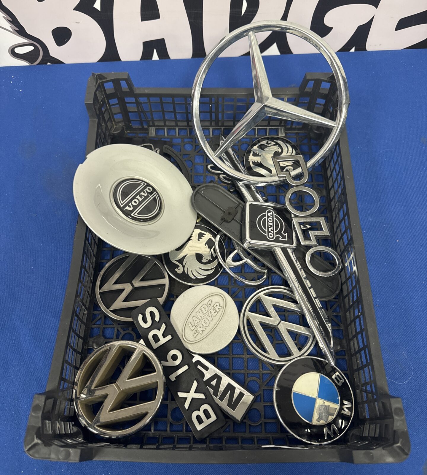 Assorted car badges and centre caps in a tray.