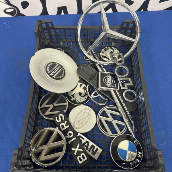 Assorted car badges and centre caps in a tray.