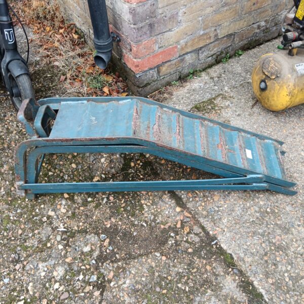 Pair of weathered steel car ramps for vehicle maintenance.