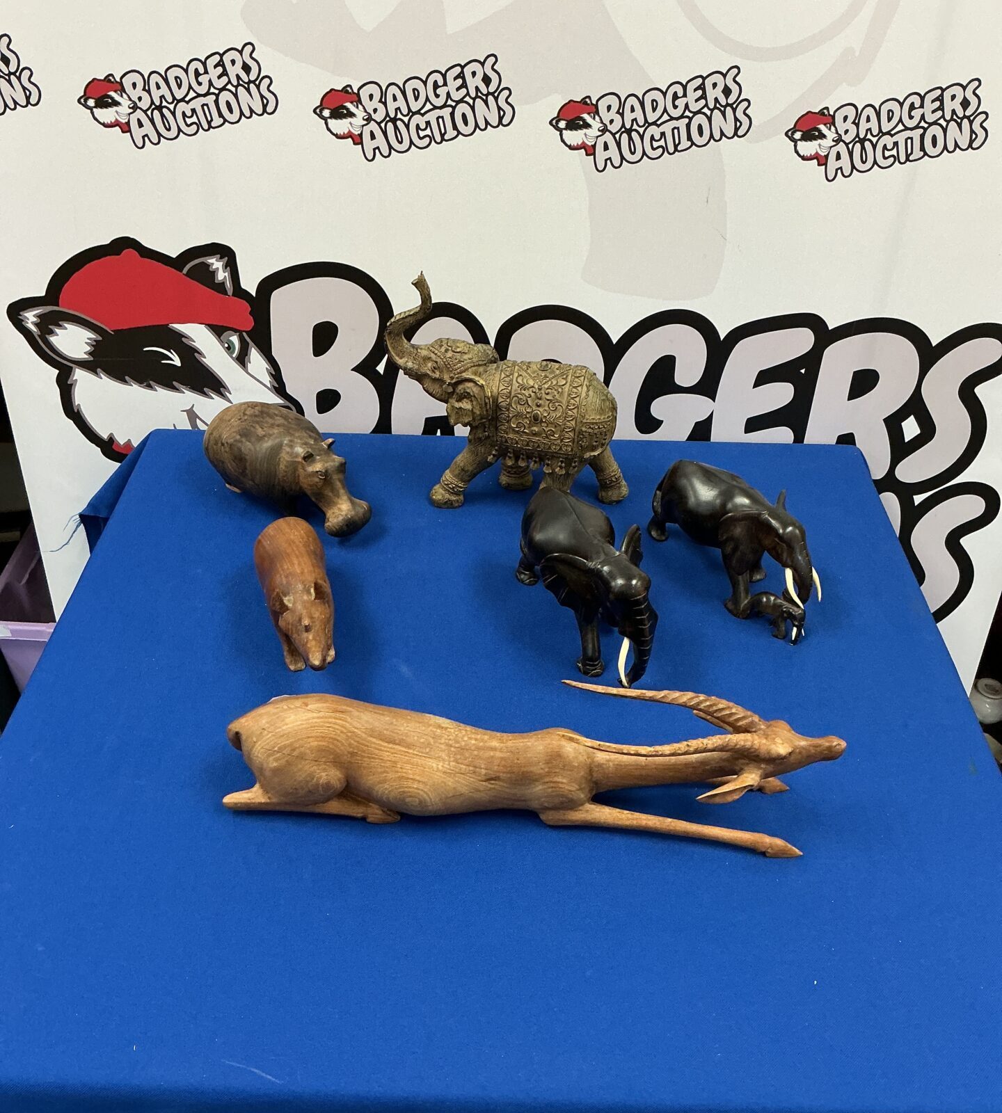 Collection of hand-carved wooden African animals, including an elephant and giraffe.