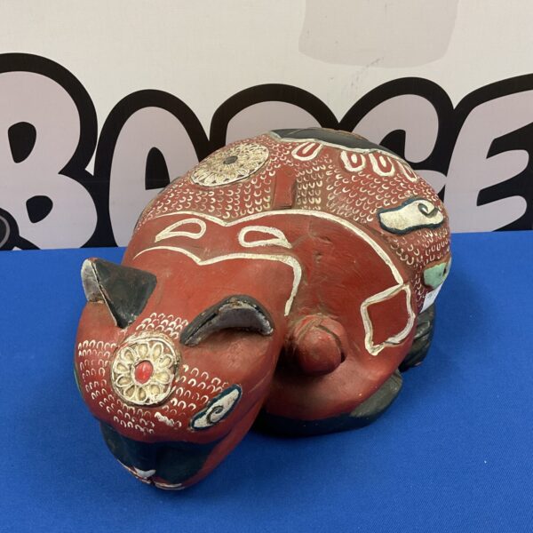 Front view of a hand-carved, painted wooden sleeping cat.