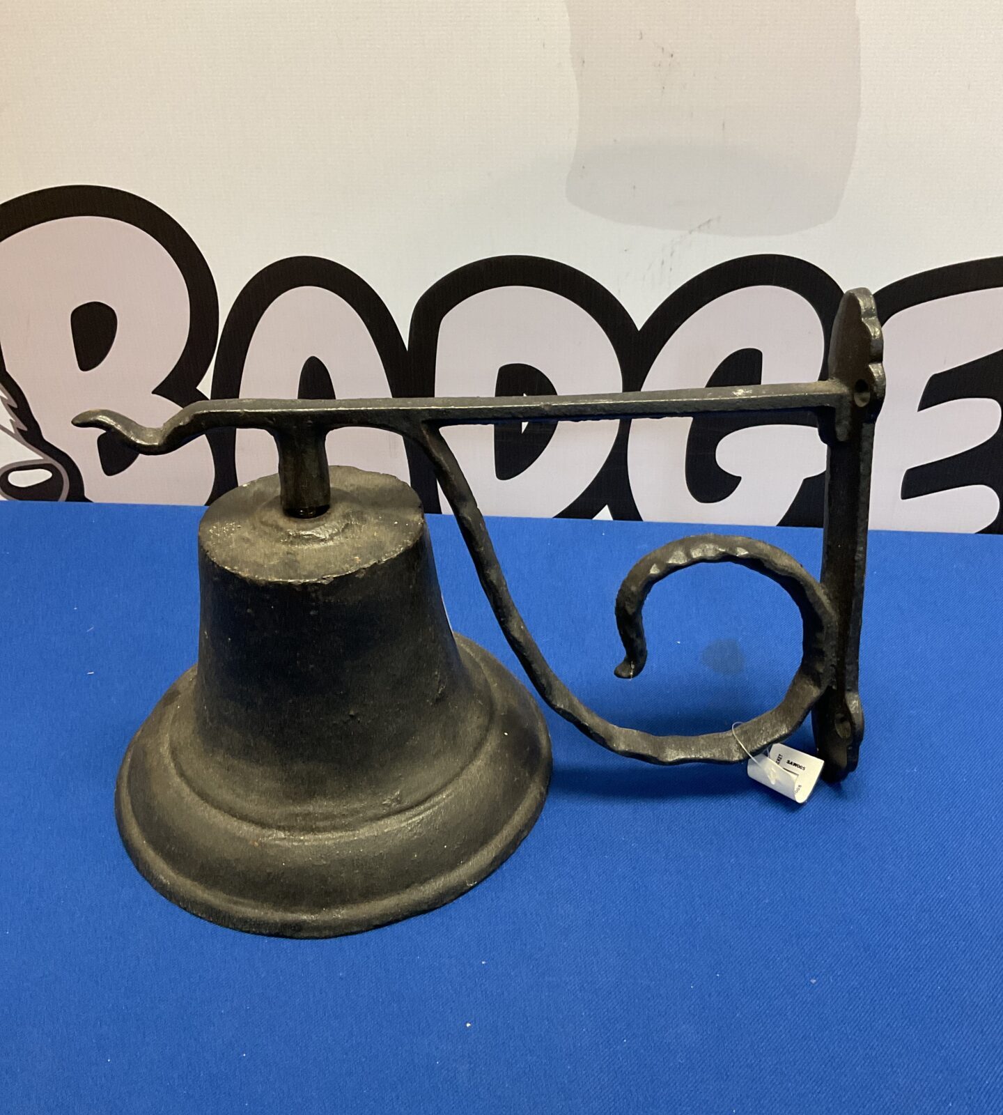 Dark cast iron bell with wall mounting bracket for garden or porch.