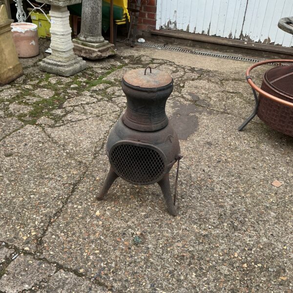 Vintage cast iron chimenea in a garden setting.