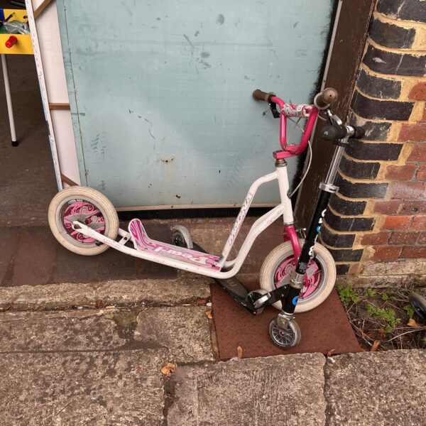 Pink children's scooter for outdoor play and developing balance.