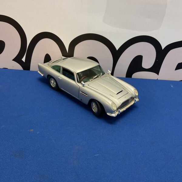 Silver Chrono Aston Martin DB5 model car on blue surface.