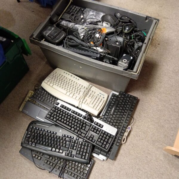 Crate full of assorted vintage and retro computer keyboards.