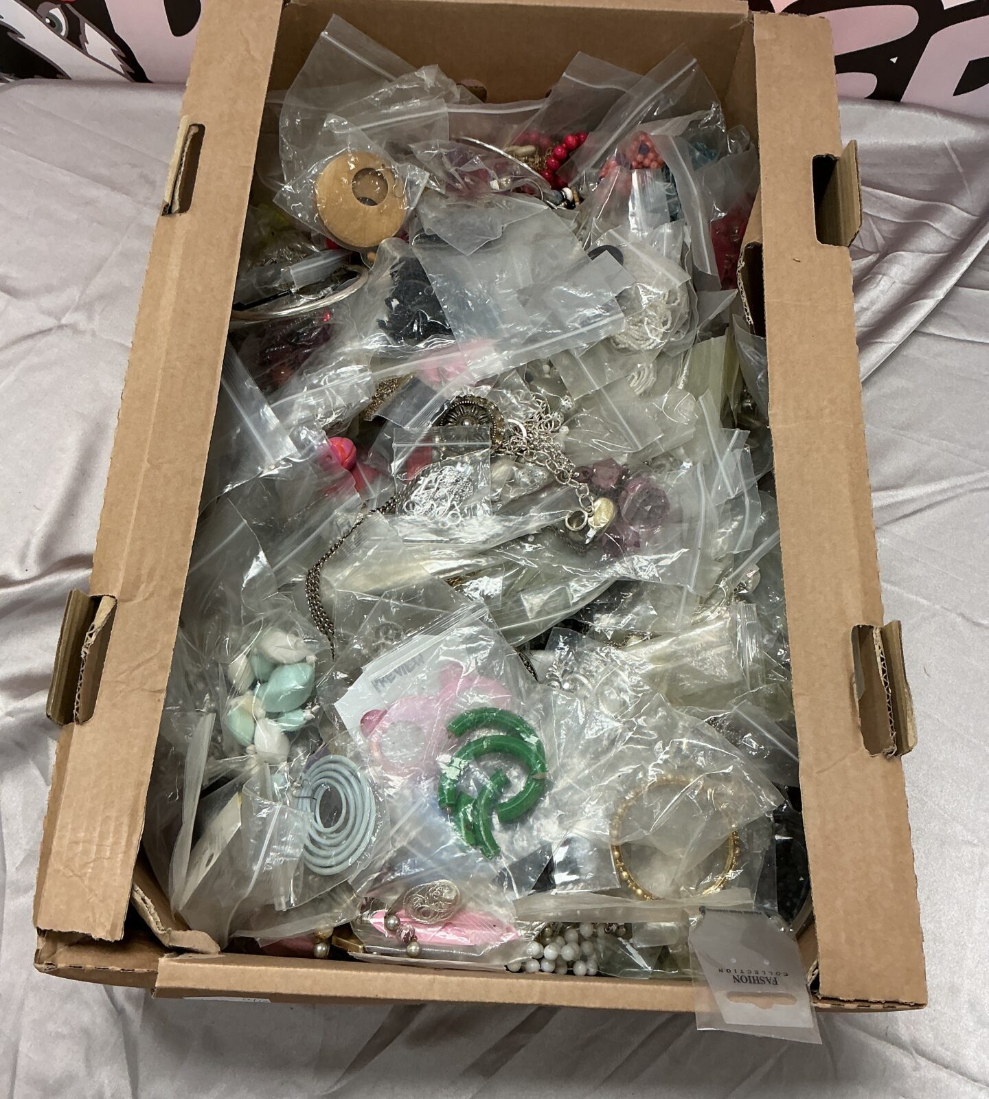 Large lot of colourful costume jewellery in a cardboard box.