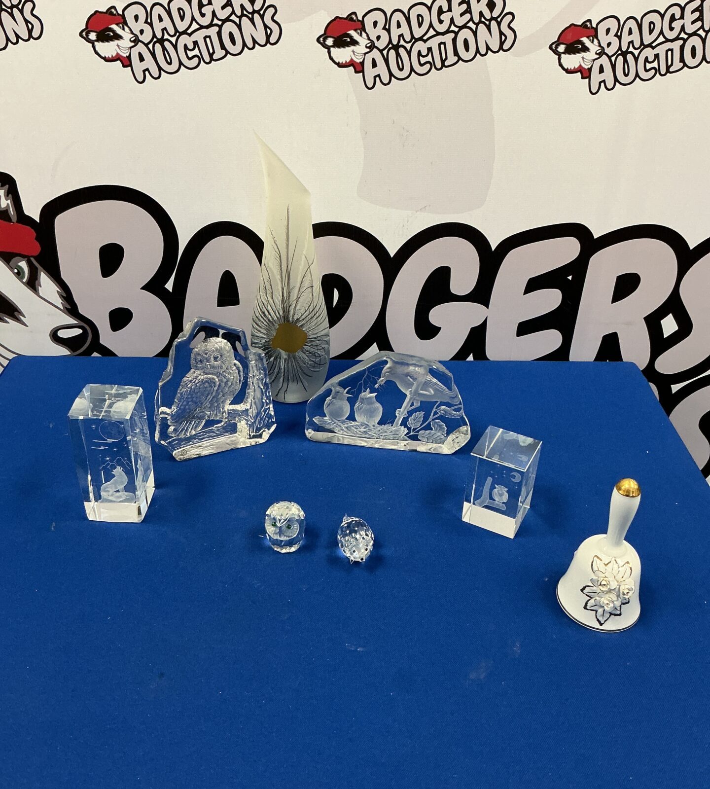 Clear crystal and glass figurines displayed on a reflective surface.