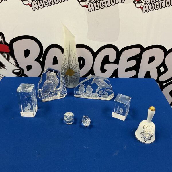 Clear crystal and glass figurines displayed on a reflective surface.