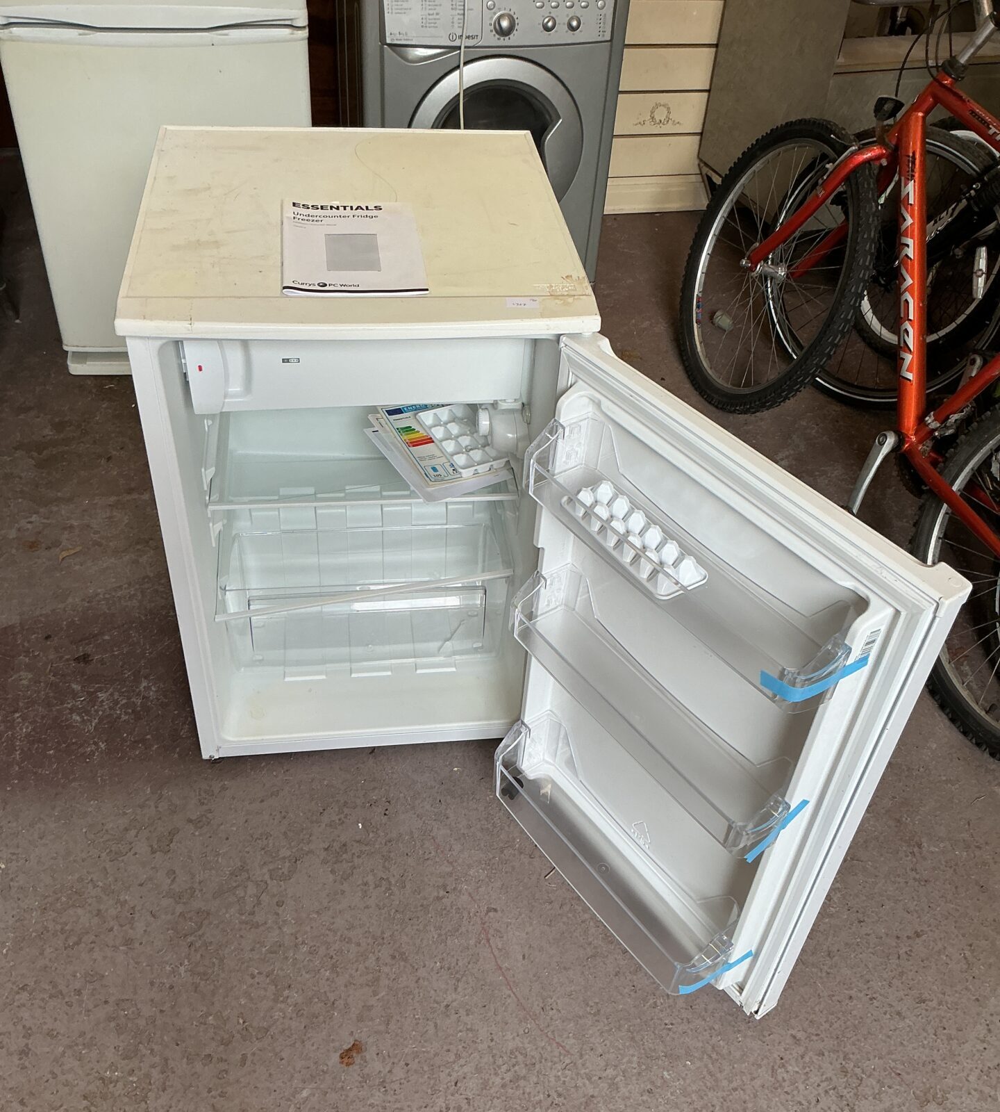 White Curry’s Essentials compact fridge in a garage setting.