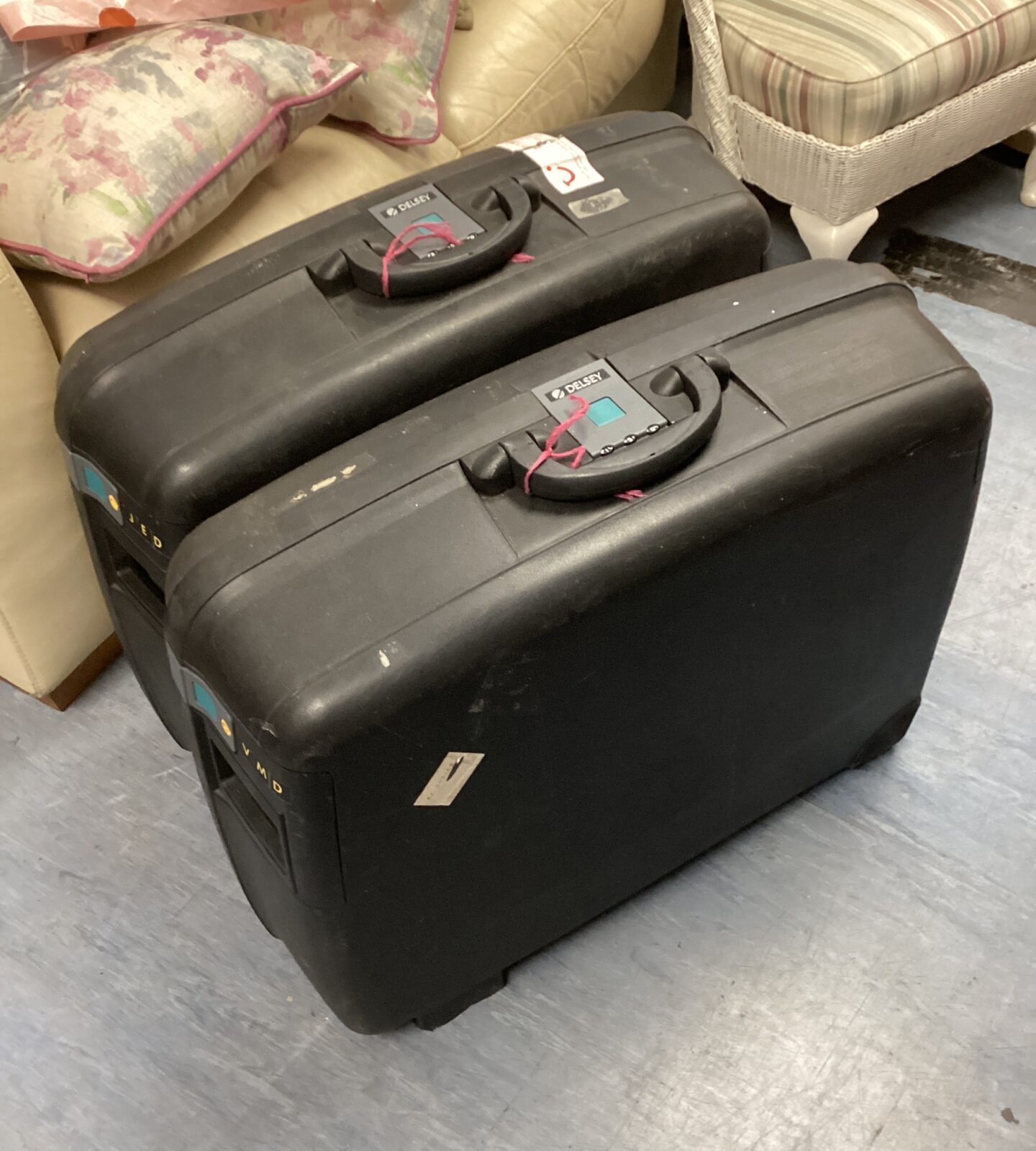 Two black Delsey suitcases stacked, showing signs of wear.