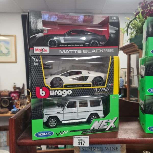 Boxed lot of three diecast model cars, including Burago, Maisto, and NEX.