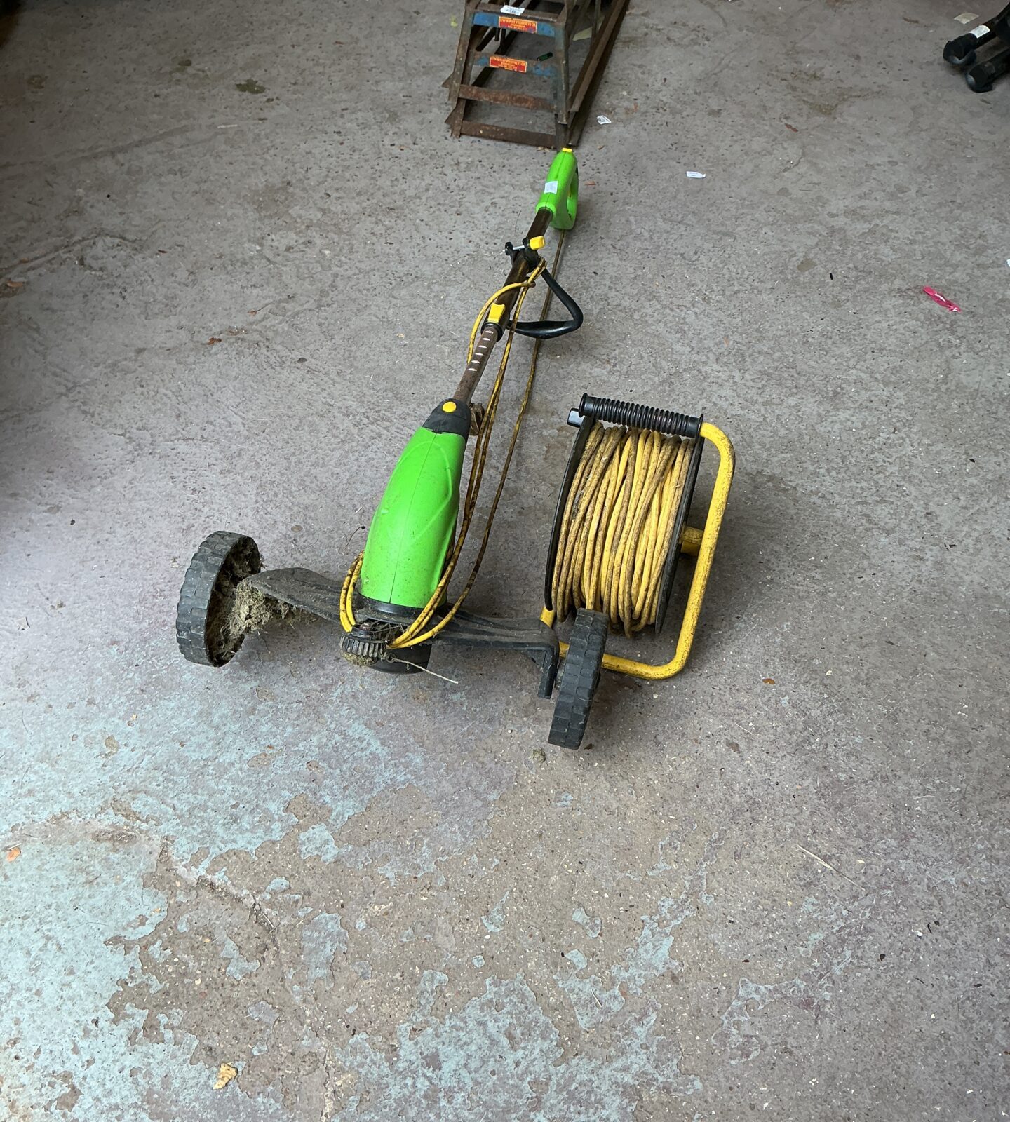 Electric garden strimmer with long power cable for lawn maintenance.