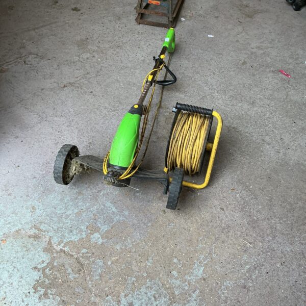 Electric garden strimmer with long power cable for lawn maintenance.
