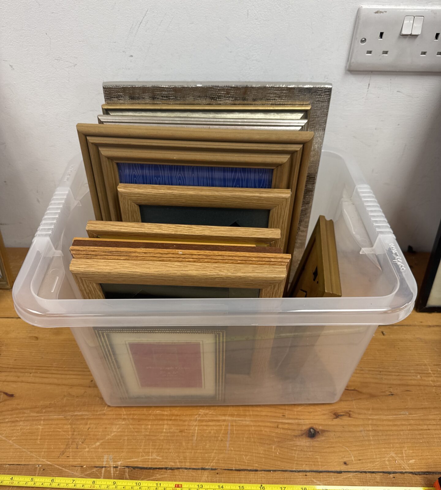 Assorted empty picture frames in a plastic storage box.