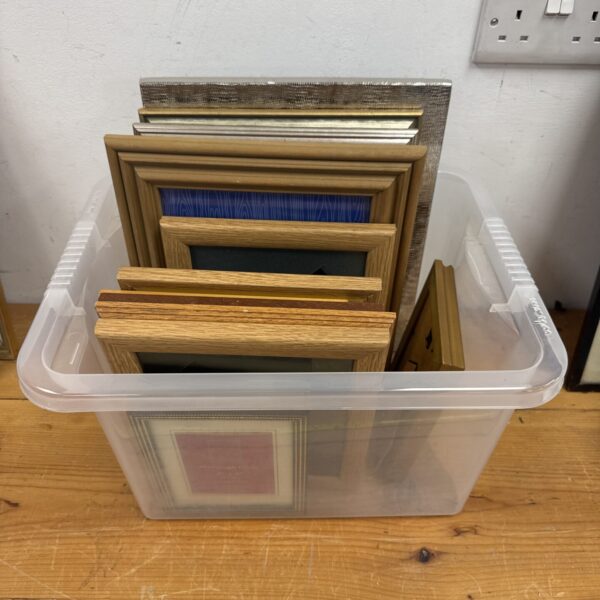 Assorted empty picture frames in a plastic storage box.