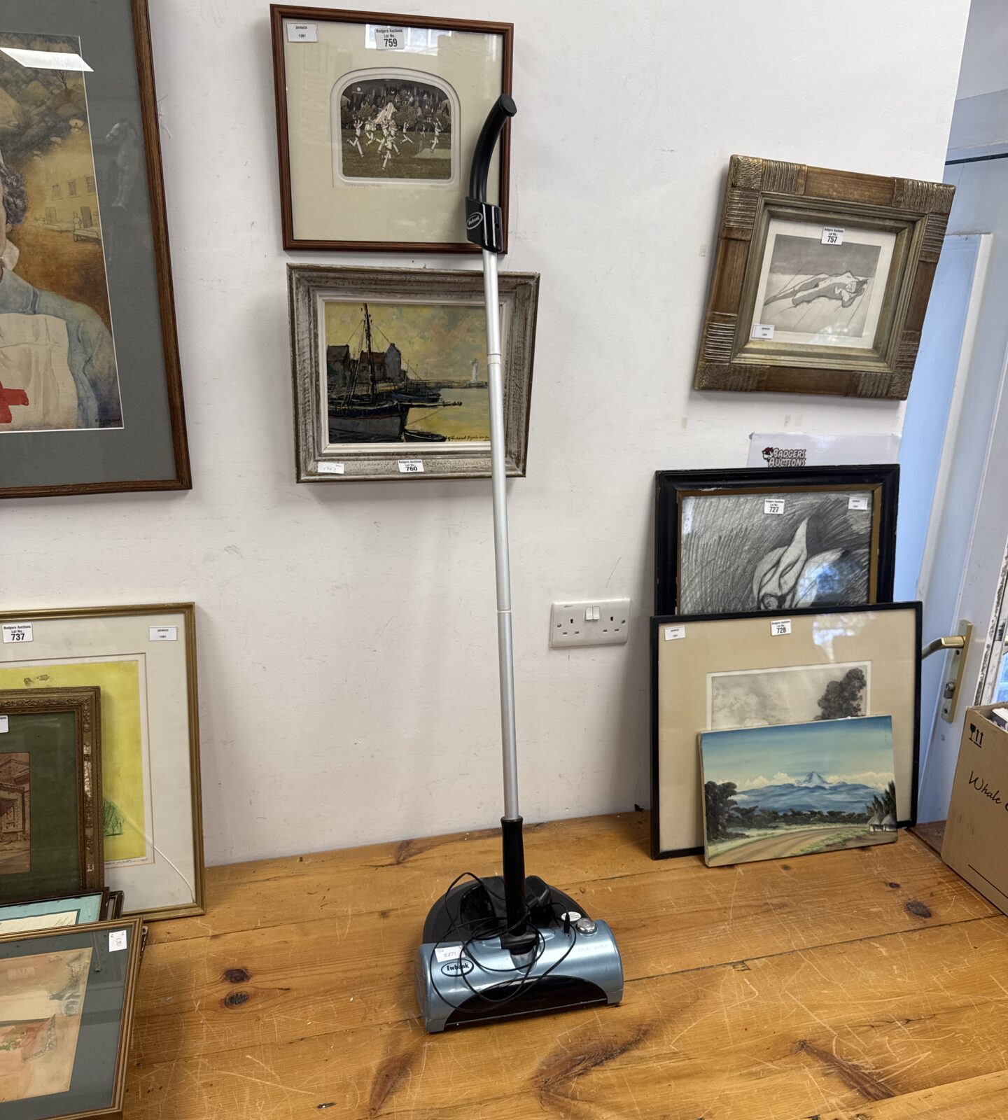 Ewbank power sweeper displayed amongst framed artwork.