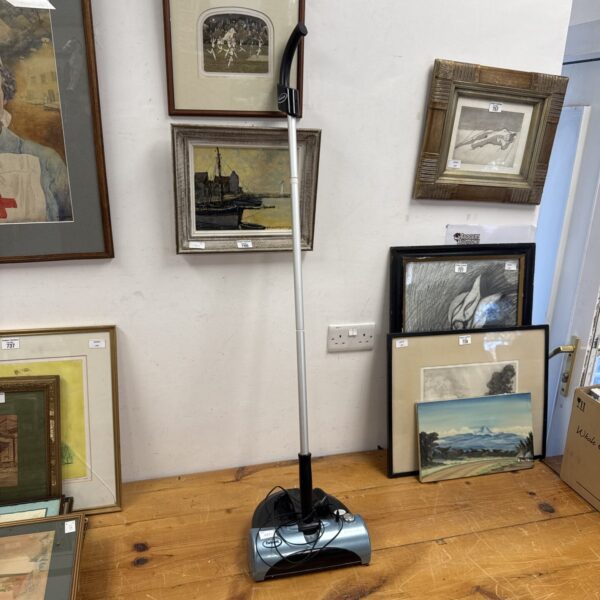 Ewbank power sweeper displayed amongst framed artwork.
